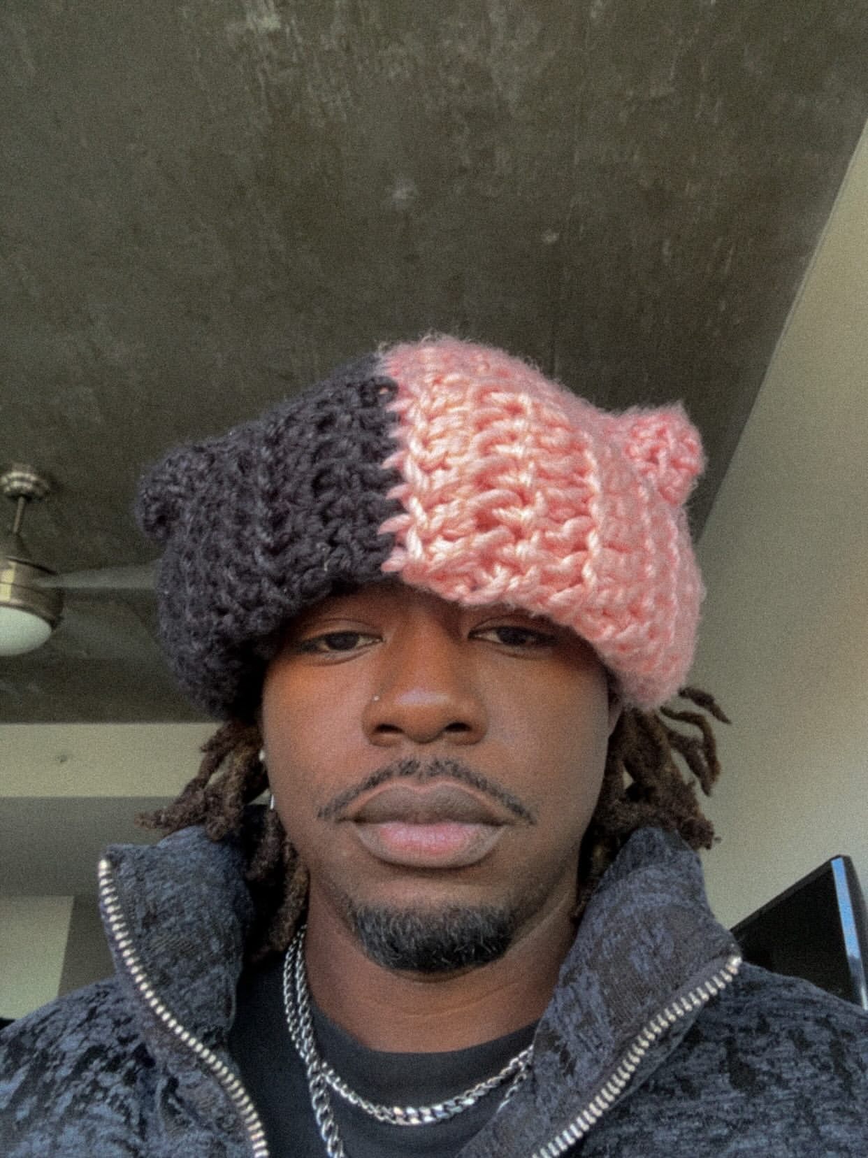 Close portrait of Yari wearing a hand-knit black and orange hat